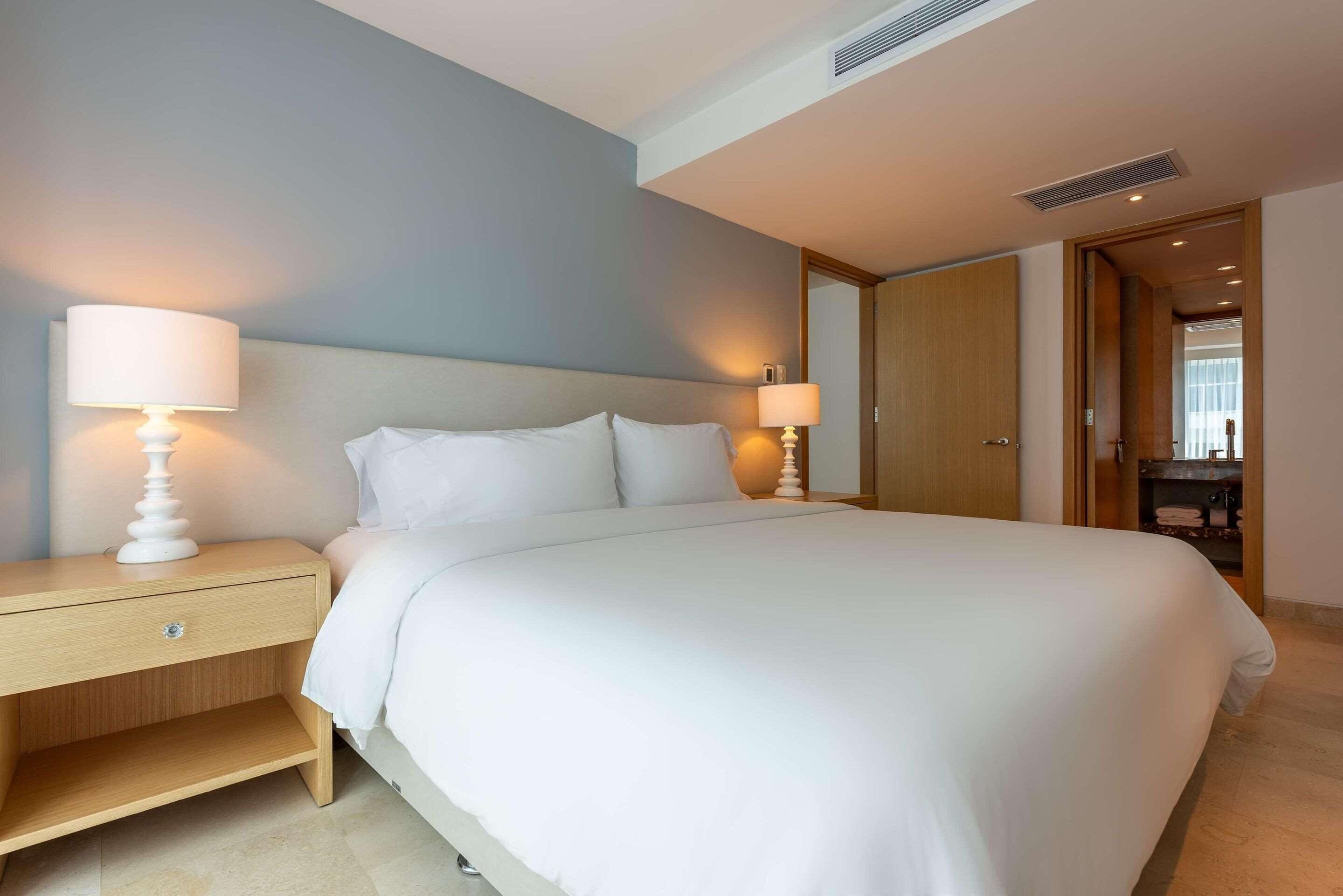 Una cama bien hecha con ropa blanca en una habitación de hotel.