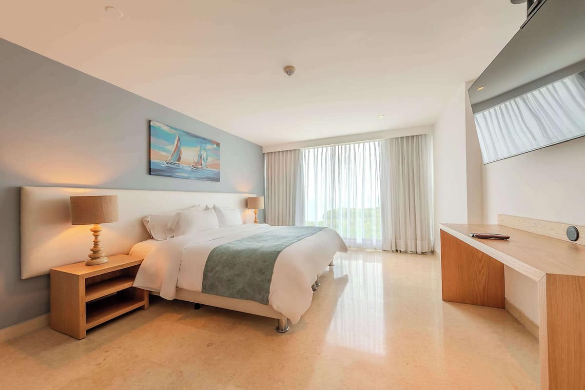 Une chambre d’hôtel moderne équipée d’un lit, d’une table de chevet, d’une lampe et d’un bureau avec une chaise.