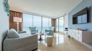 Una sala de estar moderna con un sofá, dos sillones, una mesa de centro y un televisor montado en la pared.