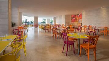 Un vaste espace dédié à la salle à manger, avec de nombreuses tables et chaises, de grandes fenêtres et un aménagement intérieur moderne.