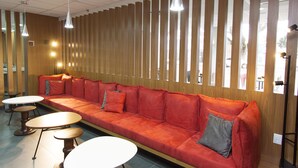 Un intérieur moderne avec un long canapé rouge, de petites tables rondes et des luminaires suspendus.