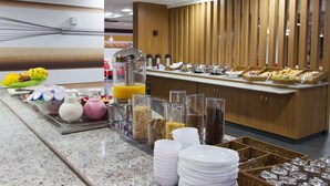 Un espace buffet proposant divers plats, un distributeur de jus et une machine à café.