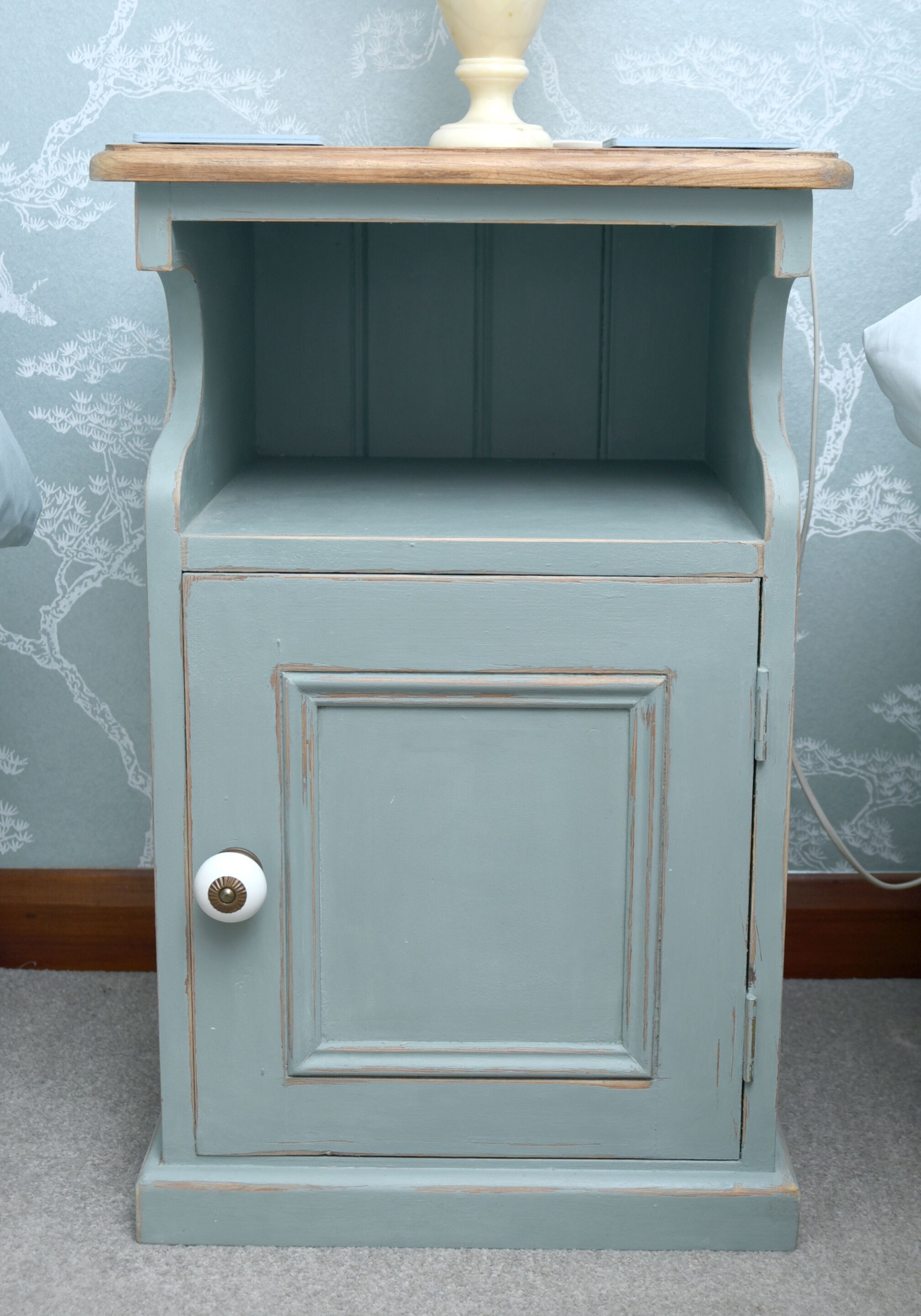 A light blue painted cabinet with a wooden top and a single door.