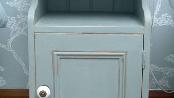 A light blue painted cabinet with a wooden top and a single door.