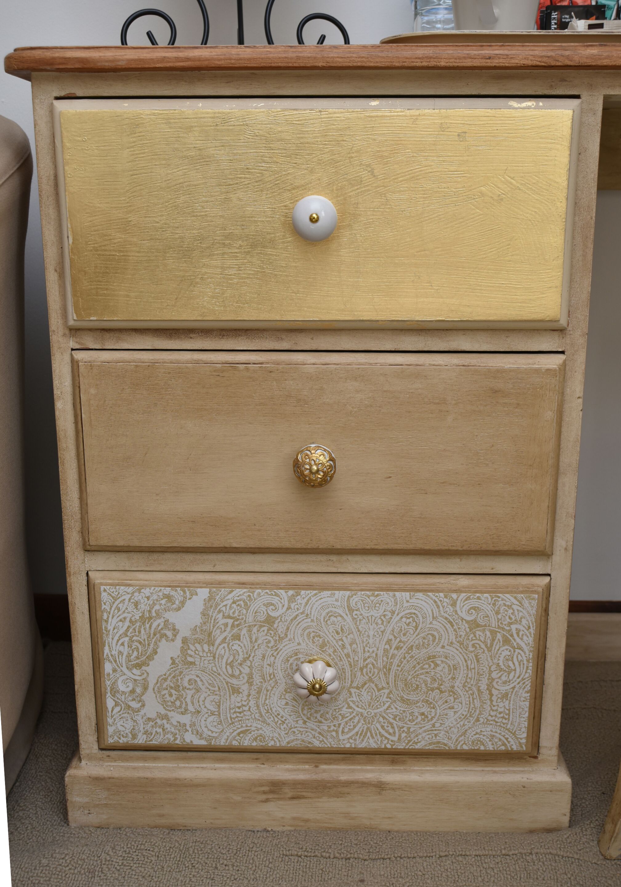 Un aparador de madera con tres cajones, cada uno con un diseño de tirador diferente.