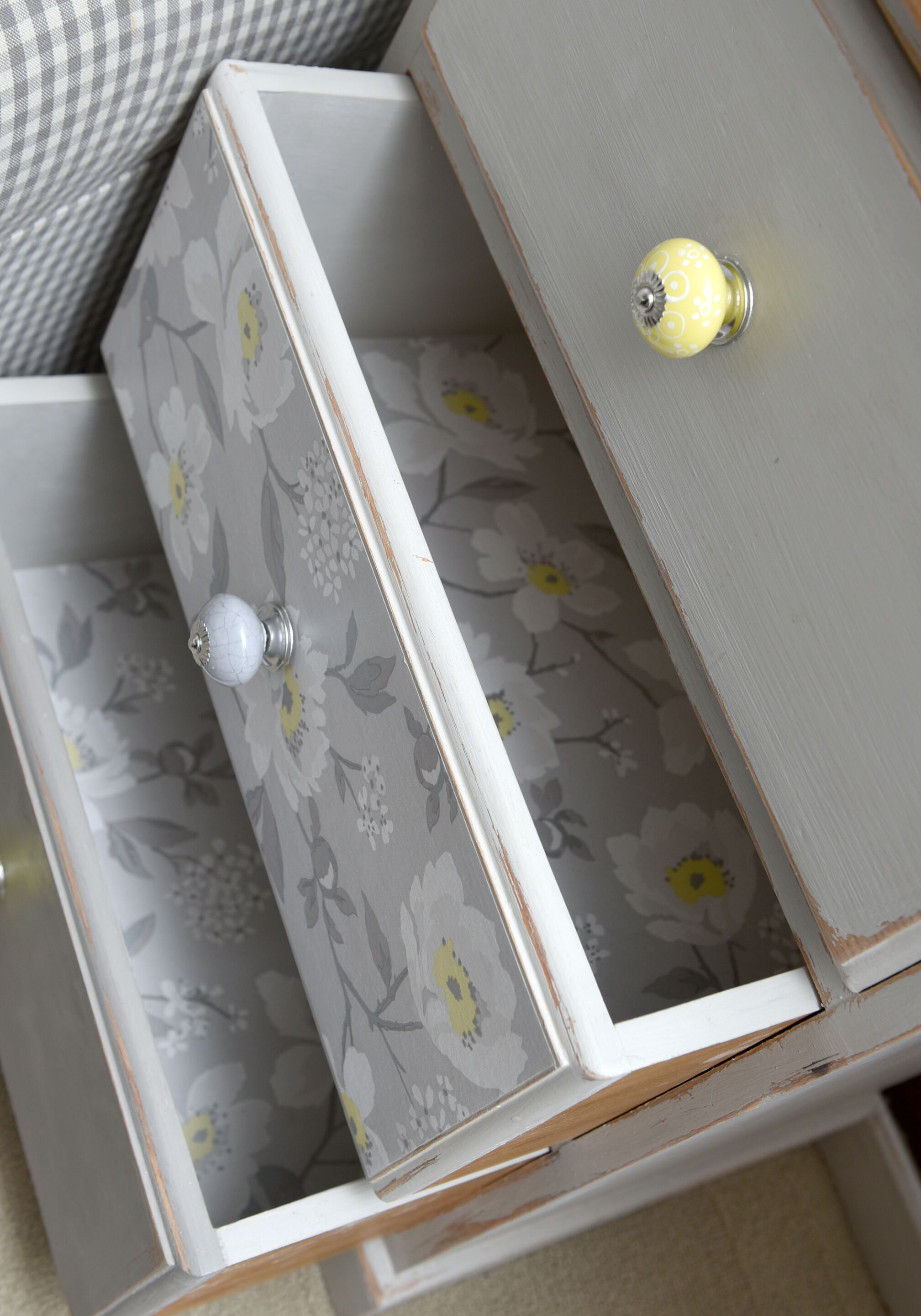 Een witte ladekast met bloemendecor en een koperen knop.
