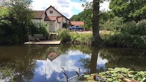 A house with a pond in front, surrounded by greenery. - Hazel Barn B&B (Diss)