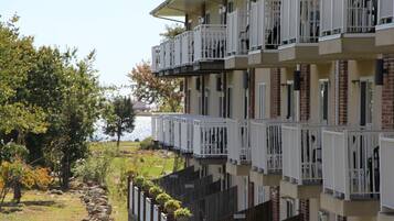 A multi-story hotel with balconies, a view of the lake, and a garden area with rocks and plants.