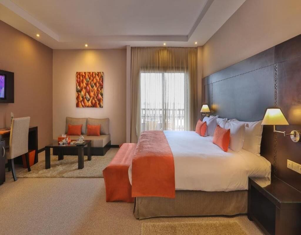 Una habitación de hotel con una cama grande, un sofá, una mesa de centro y una televisión.