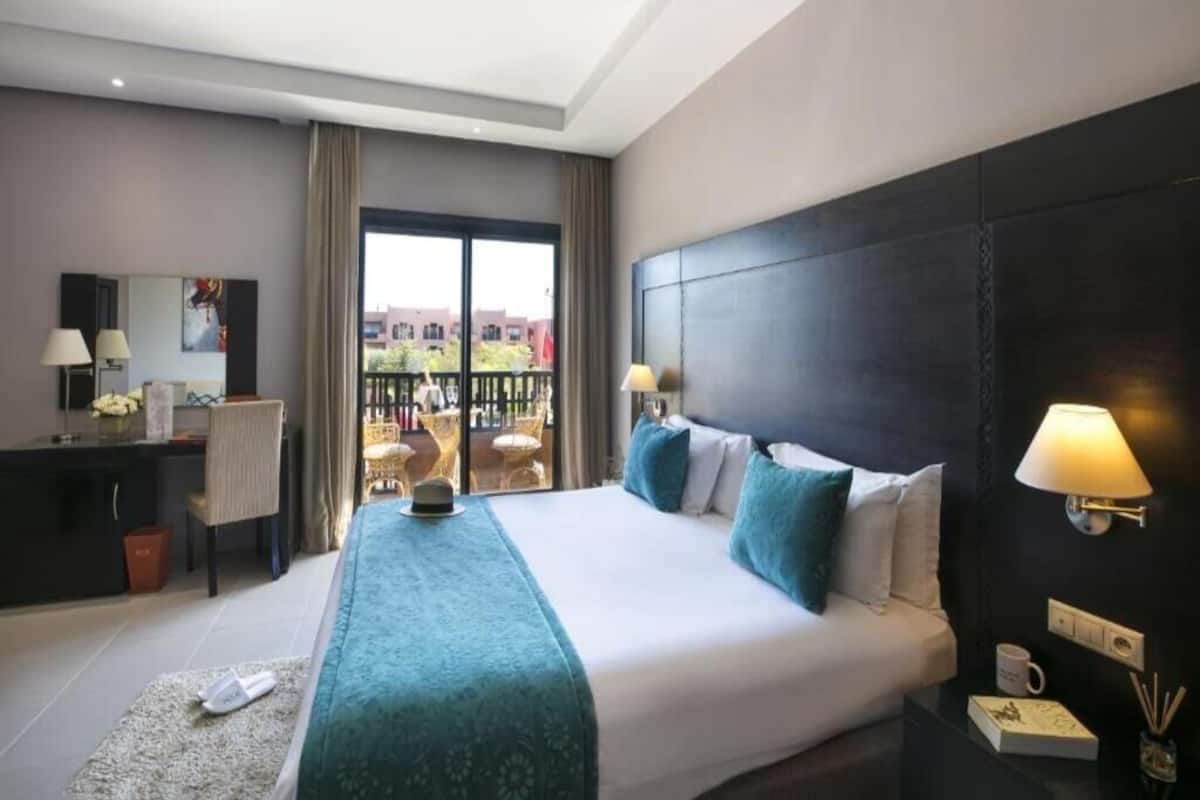 Habitación de hotel con una cama grande, un escritorio y un balcón con vistas.