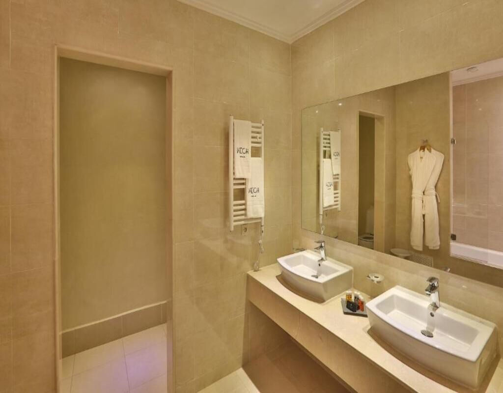 Un baño moderno con dos lavamanos, un espejo grande y barras para toallas.