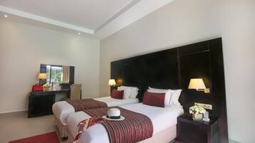 Habitación de hotel con dos camas, un escritorio y una mesita de noche con lámparas.