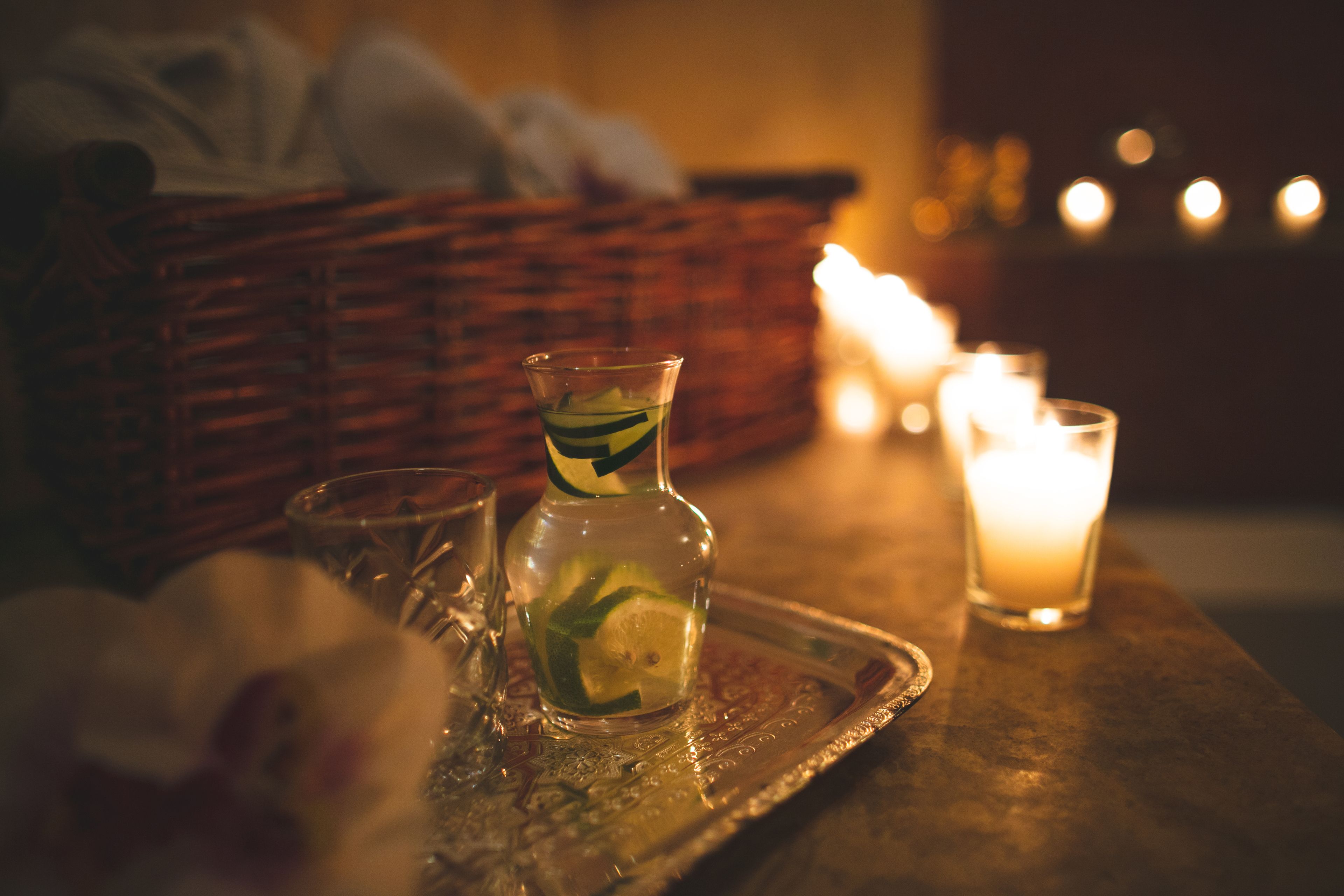 A tray with a glass of water, a glass with a drink, and a candle on a table.