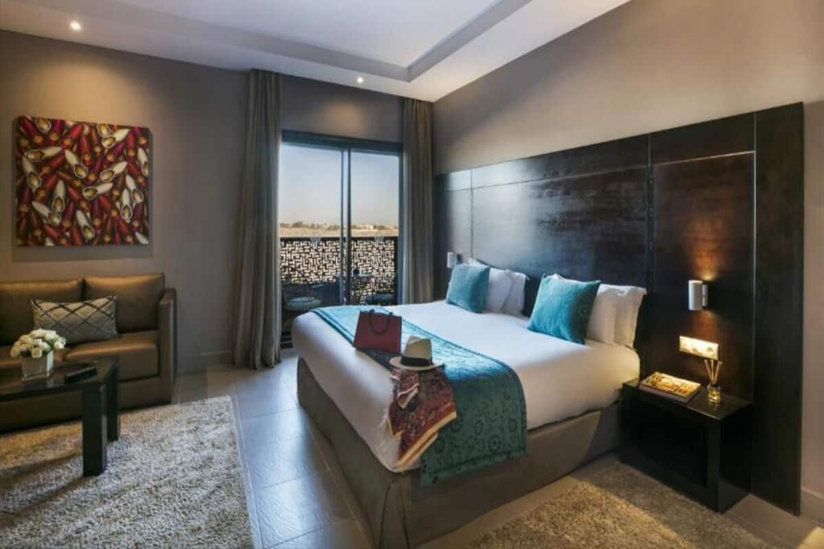 Una habitación de hotel moderna con una cama grande, un sofá, una mesa de centro y vistas por la ventana.