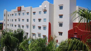 Un hotel con fachada blanca, numerosas ventanas y una pared de acento roja.