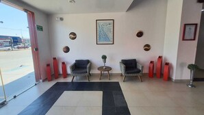 Un vestíbulo con dos sillones de mimbre, una mesita redonda y un mapa en la pared.