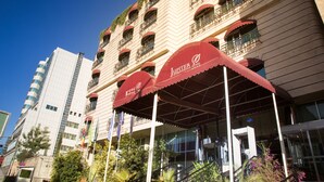 A hotel with multiple balconies, red awnings, and a modern facade. - Jupiter International Hotel Bole (Addis Ababa)