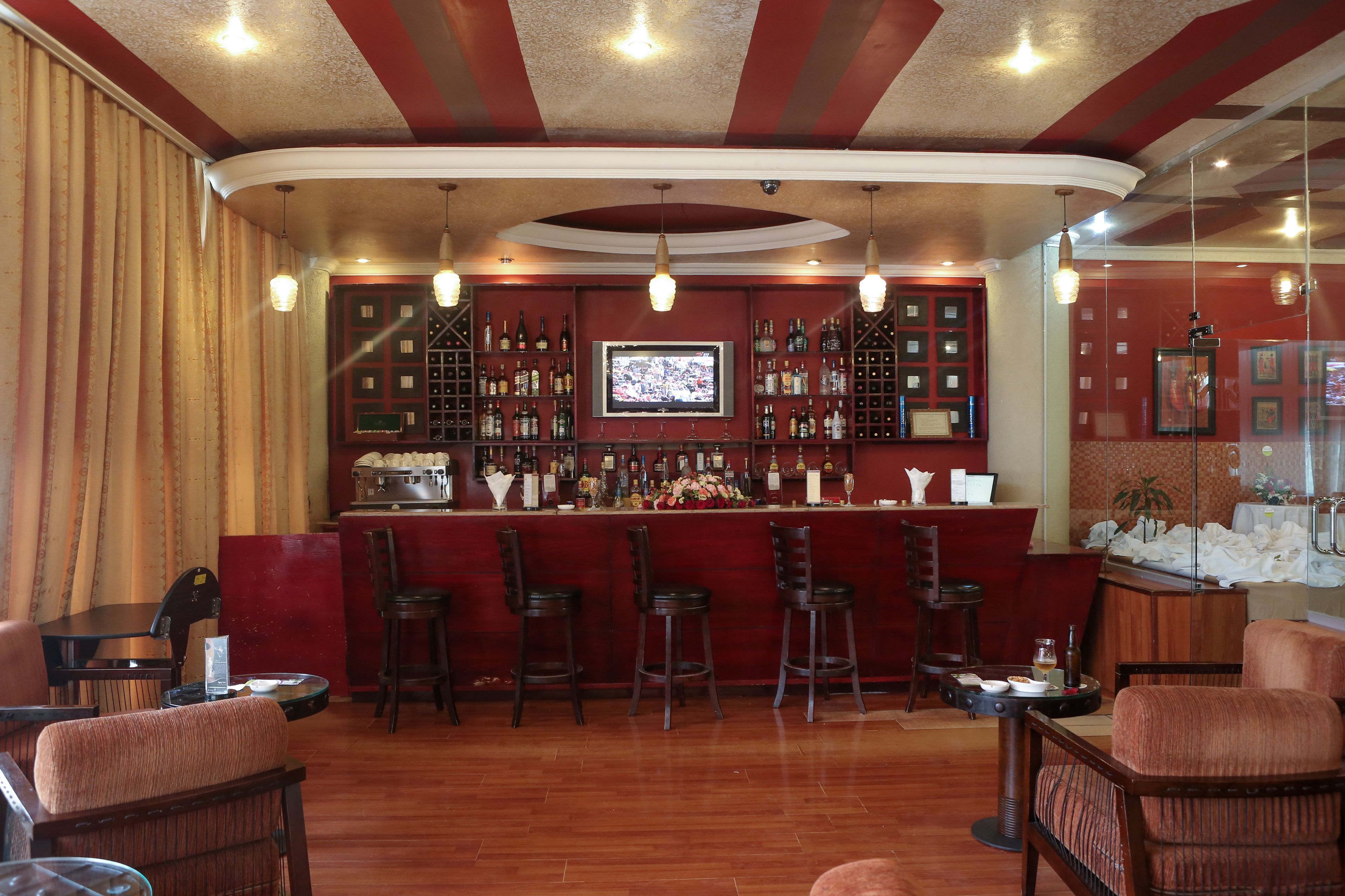 A bar area with a curved ceiling, wooden bar counter, and multiple stools.