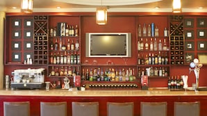 A bar with a television, shelves of liquor, and a coffee machine. - Jupiter International Hotel Bole (Addis Ababa)