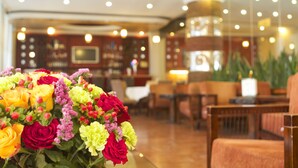A hotel lobby with a floral arrangement, seating area, and a television screen. - Jupiter International Hotel Bole (Addis Ababa)