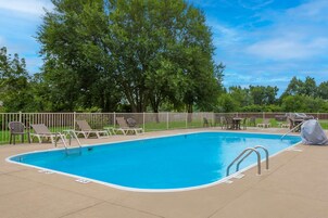 Una piscina al aire libre, sillones reclinables de piscina