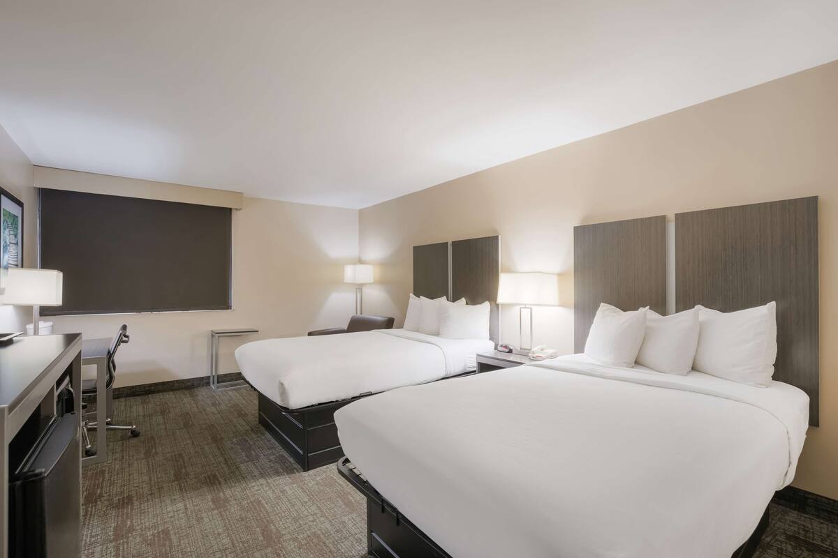 Ein Hotelzimmer mit zwei Betten, einem Schreibtisch und einem Stuhl.