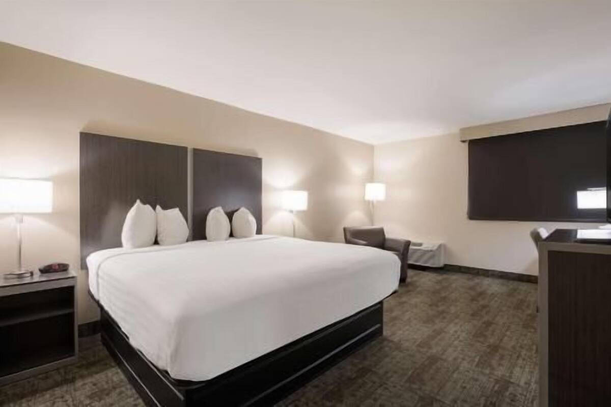 Ein Hotelzimmer mit einem großen Bett, Nachttischen, einem Schreibtisch und einem Fernseher.