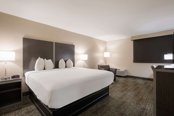 A hotel room with a large bed, two bedside lamps, a desk, and a flat-screen TV.