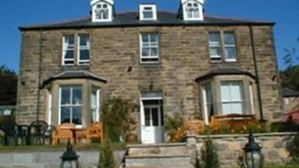 A stone building with a symmetrical facade, a central entrance, and a small porch area. - The Haven (Morpeth)