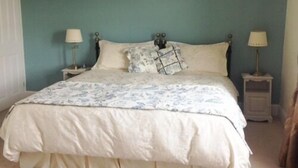 A bedroom with a bed, two bedside tables, and a wall-mounted light fixture. - The Haven (Morpeth)