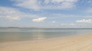 Een strand met heldere lucht en rustig water.
