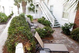 Une terrasse avec des sièges extérieurs et un escalier menant à un bâtiment blanc.