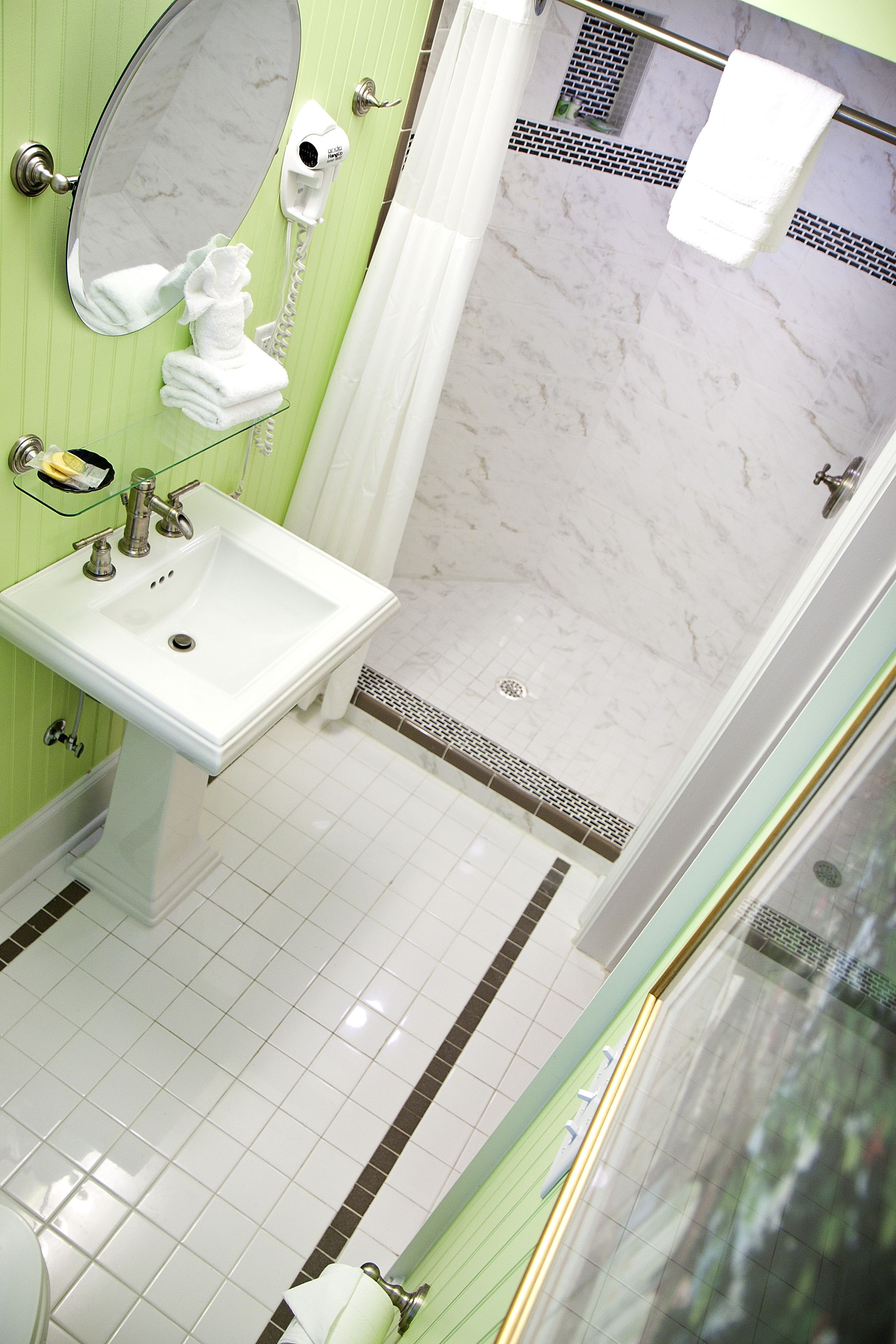 A bathroom with a sink, mirror, and shower.