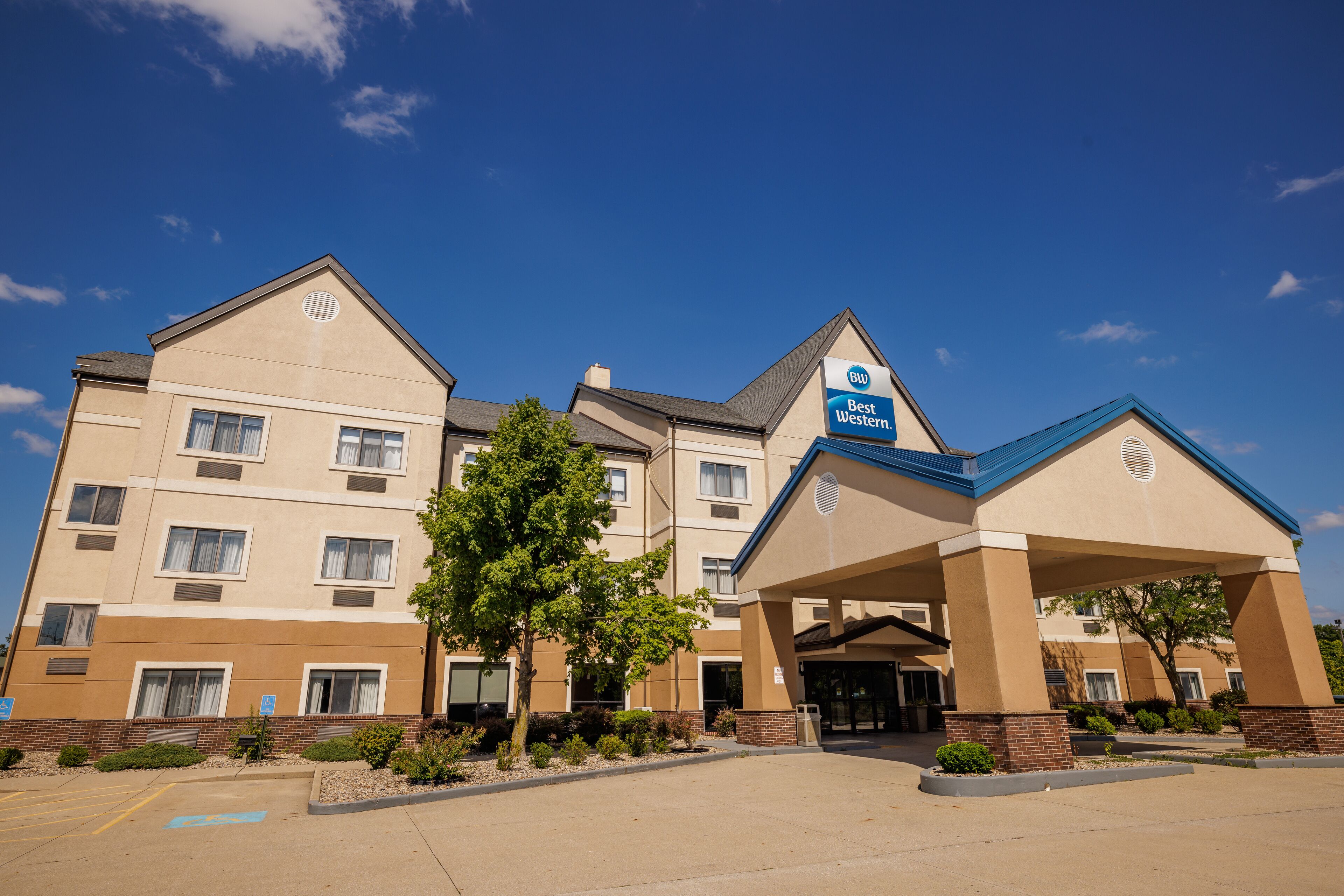A multi-story hotel with a prominent Best Western sign, a covered entrance, and a parking lot.