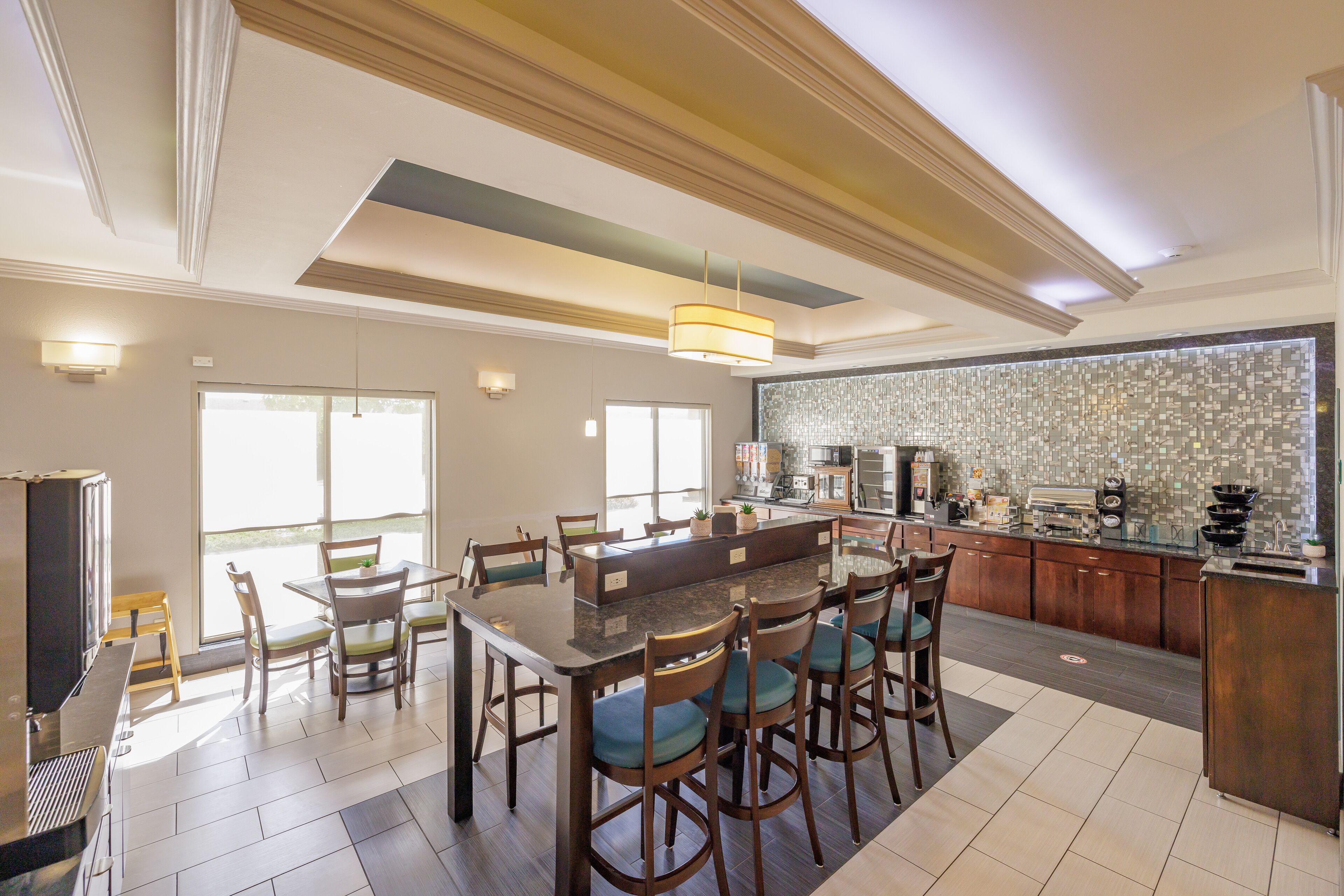 A modern kitchen with a large island, bar stools, and a dining table.