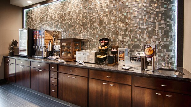 Ein Hotel-Rezeptionsbereich mit einer Wand aus Marmorplatten, einer Kaffeestation und einer Auswahl an Gebäck und Waffeln.