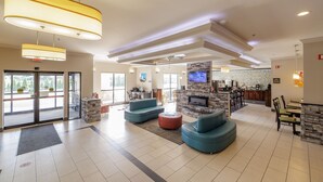 Eine großzügige Lobby mit einer Sitzecke, einem Kamin und einem Fernseher.