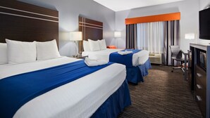 Ein Hotelzimmer mit zwei Betten, einem Schreibtisch, einem Fernseher und einer Klimaanlage.