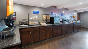 Un bar pour le petit-déjeuner équipé d’une machine à café, d’un grille-pain et d’une vitrine contenant des pâtisseries.