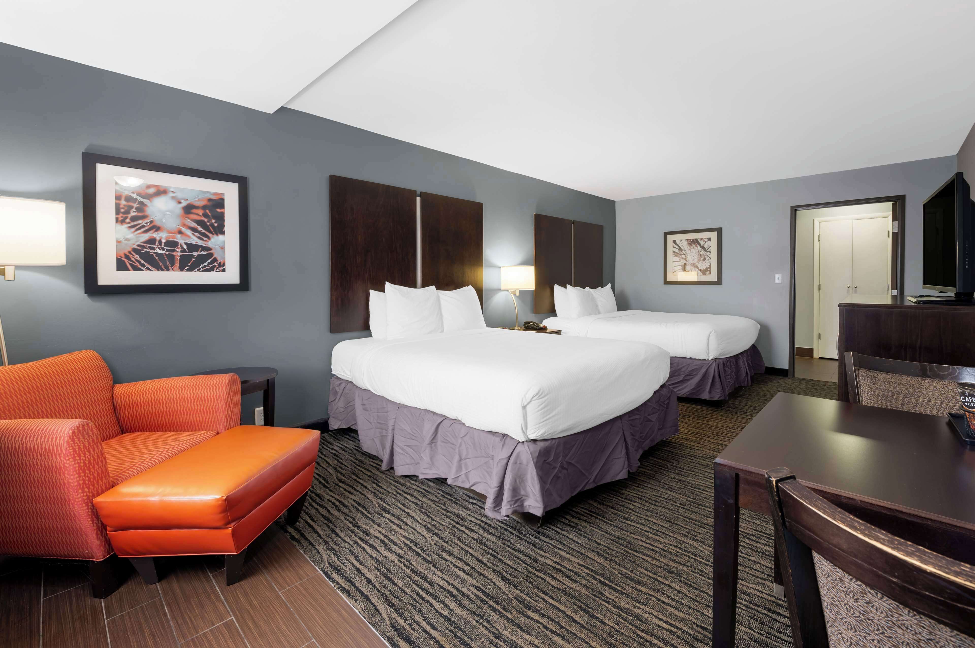 Habitación de hotel con dos camas, un sofá, un escritorio y una televisión.