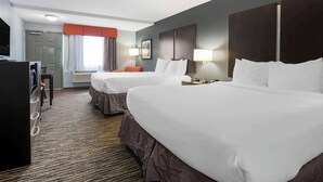 Une chambre d’hôtel avec deux lits, un bureau avec une télévision, une fenêtre avec des rideaux et une tête de lit fixée au mur.