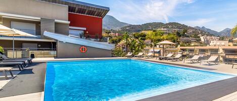 Una piscina con sillones de descanso, un flotador salvavidas y vistas a un paisaje montañoso.