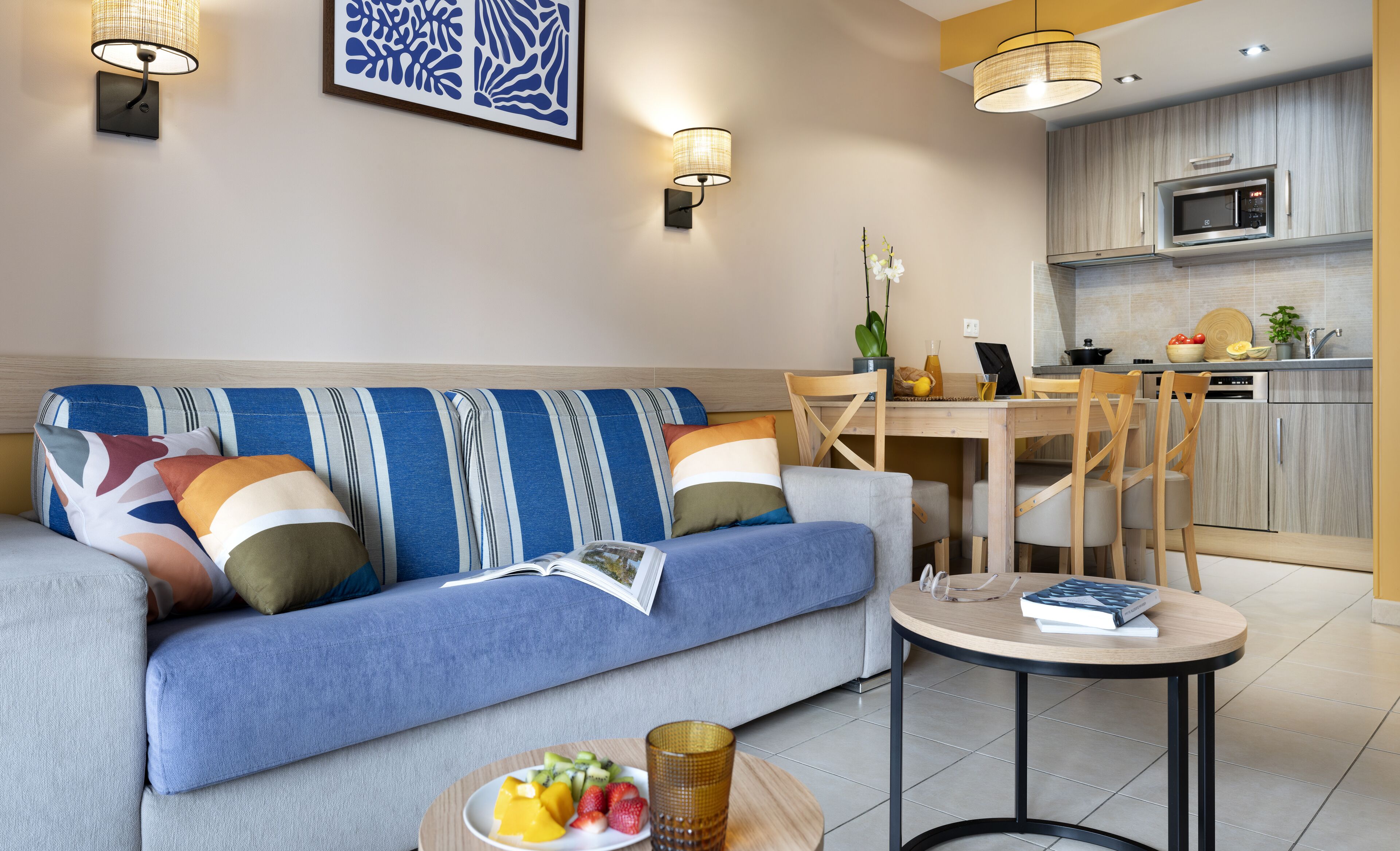 Una sala de estar moderna con sofá, mesa de comedor y zona de cocina.