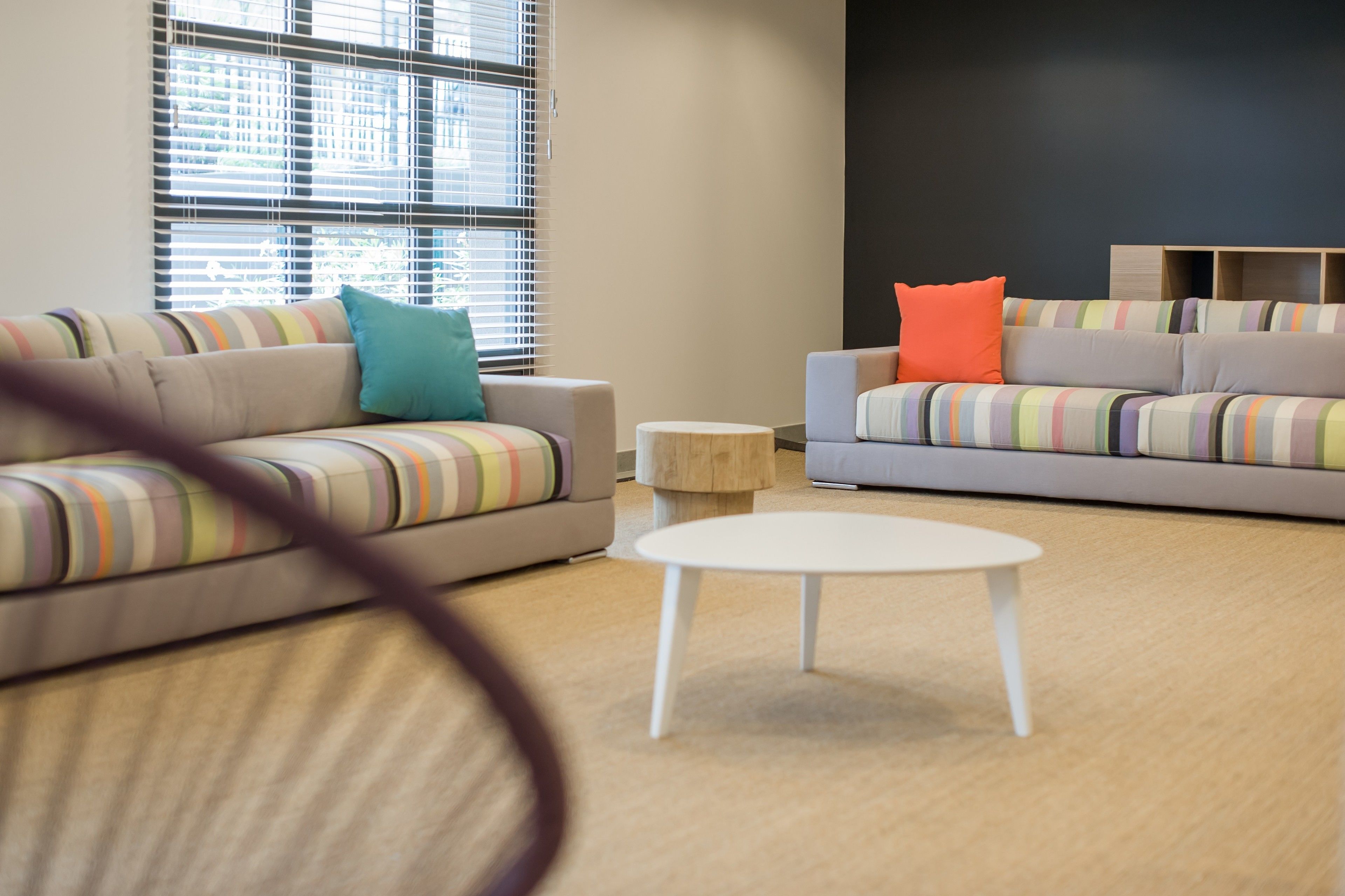 A modern living room with striped sofas, a round coffee table, and a wooden side table.