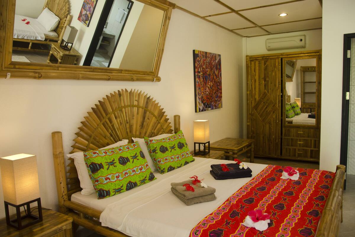 A room with a bed, a mirror, a painting, and a wardrobe.