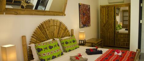 A room with a bed, a mirror, a painting, and a wardrobe.