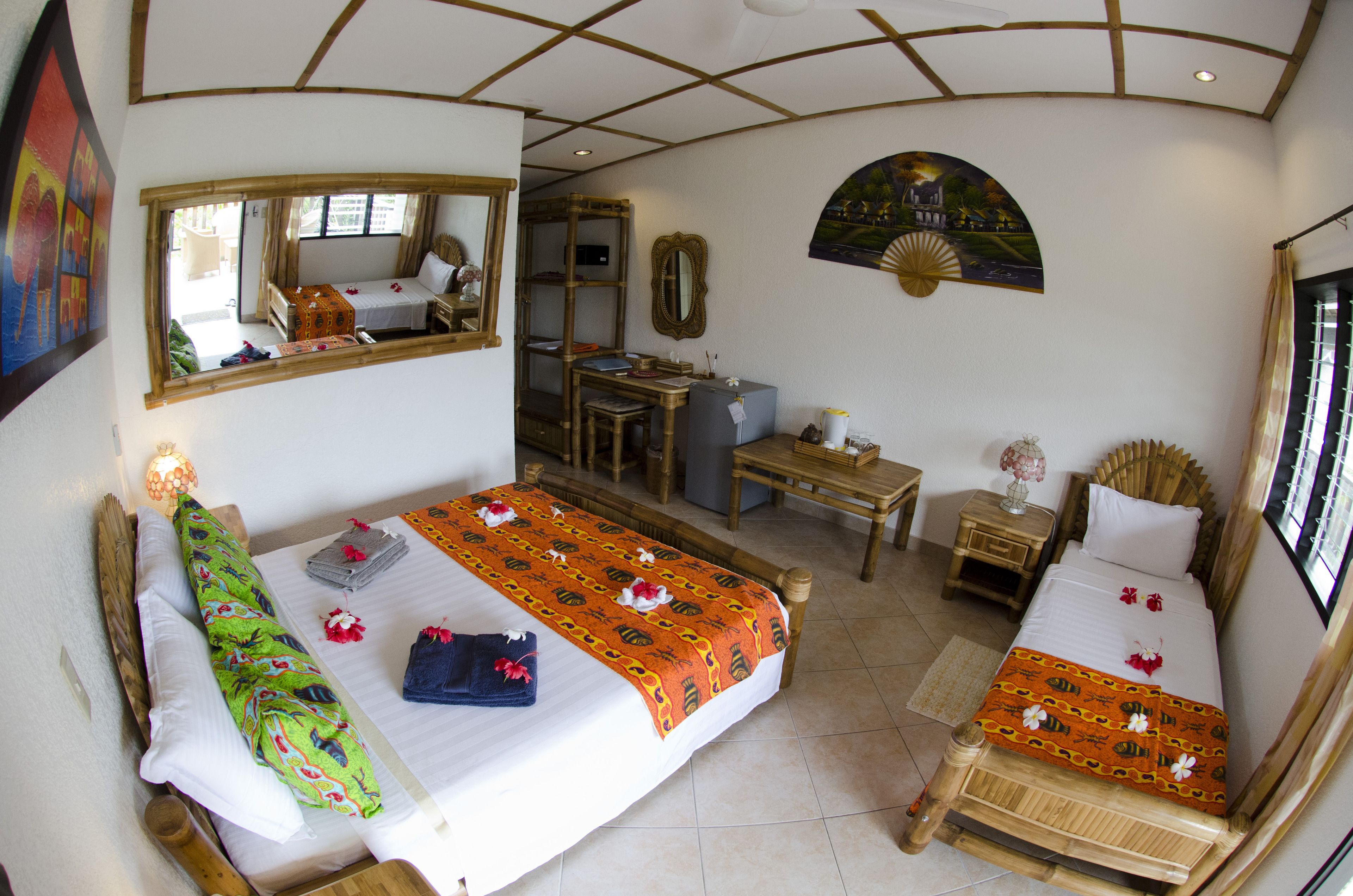 A room with two beds, a desk, a chair, a mirror, and a window.
