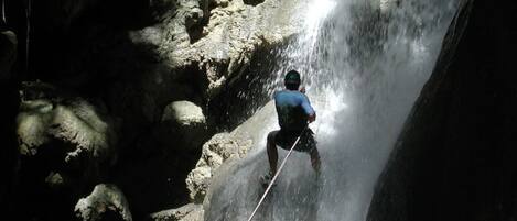A person rappelling down a rocky waterfall.