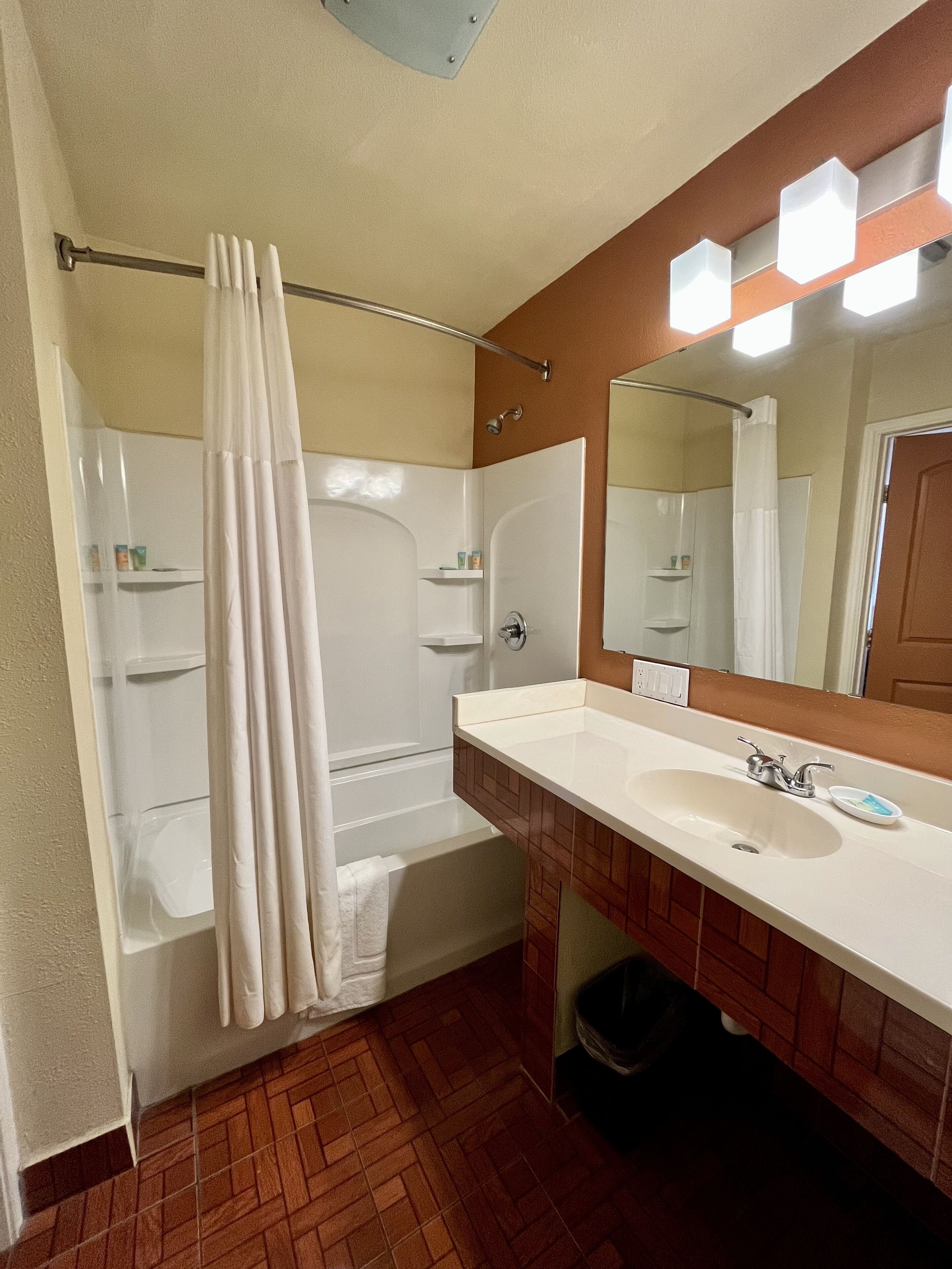 A bathroom with a bathtub, a shower, a sink, and a mirror.