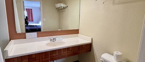 A bathroom with a white sink, a mirror, a toilet, and a towel rack.